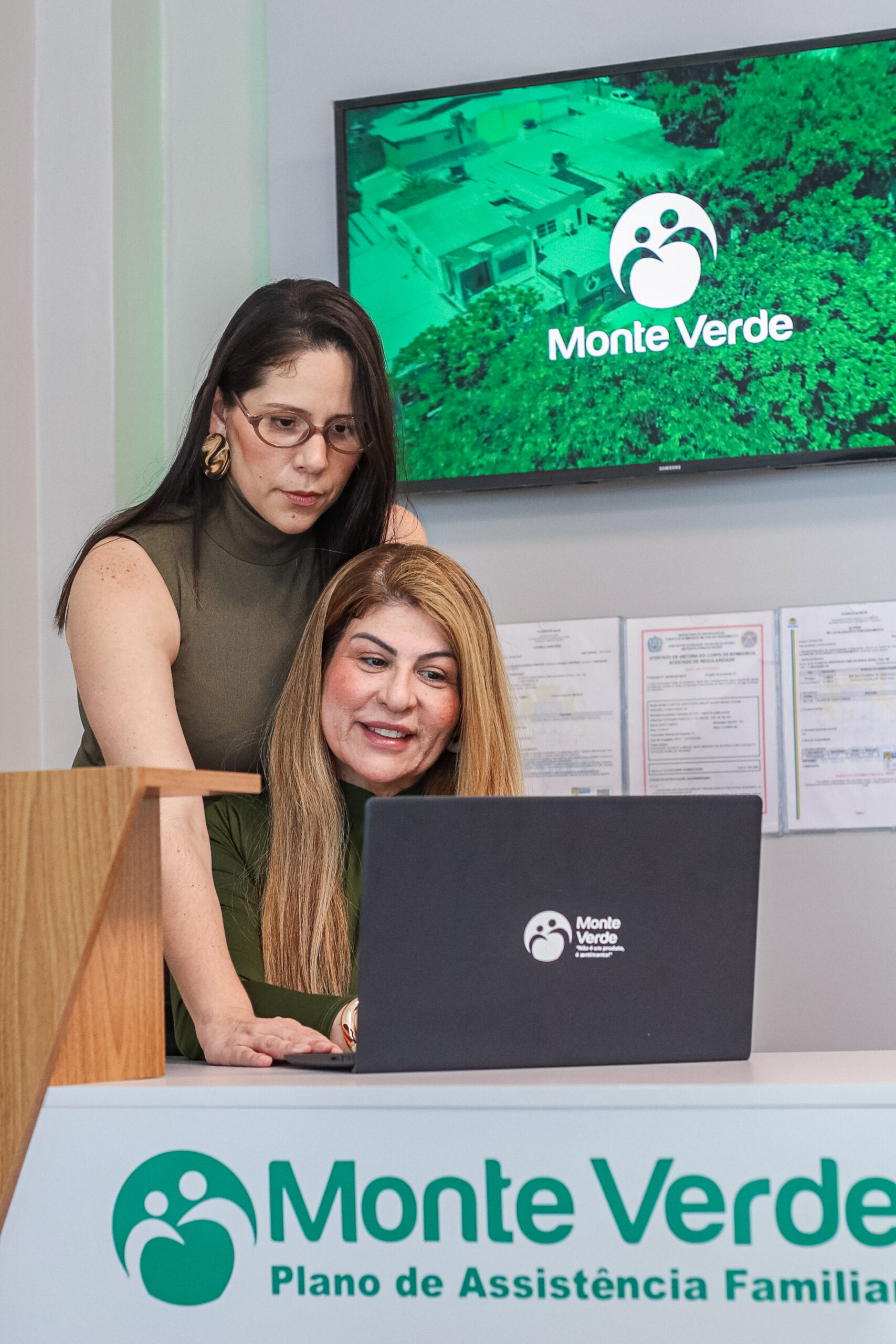 Atendimento na recepção da Monte Verde, com duas mulheres diante de um notebook